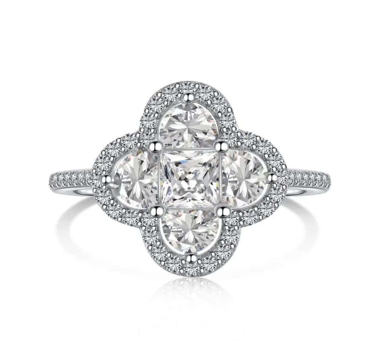 A silver plated ring with a larger central clover piece made up of different shaped white diamonds mainly mini square and semi circular diamonds with miniature white diamonds embroidered around the central piece
