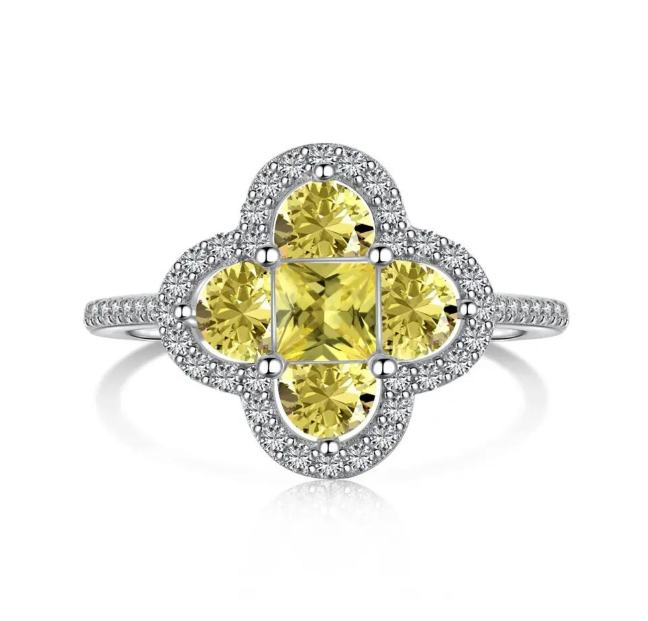 A silver plated ring with a larger central clover piece made up of different shaped yellow diamonds mainly mini square and semi circular diamonds with miniature white diamonds embroidered around the central piece 