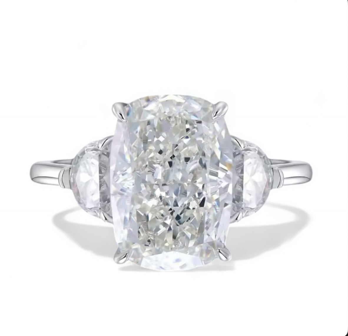 A silver plated ring with a white oval radiant crushed cut central diamond with 2 semi circular embroidery diamonds guarding each side of the central piece. The central diamond has a slightly yellow tint but mainly appears white 