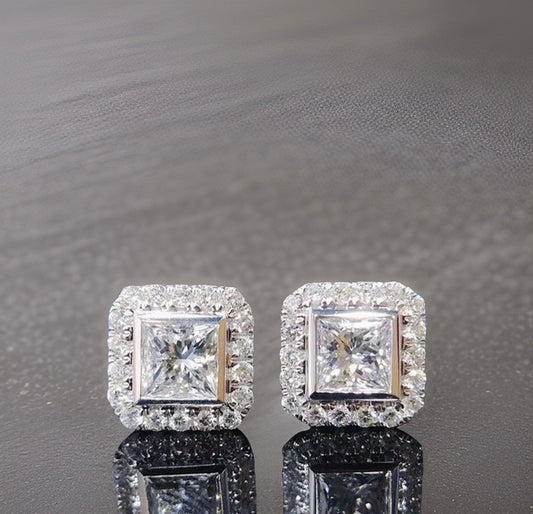 Square princess cut silver studs with miniature white diamonds embroidered around the rest of the plating surrounding the larger central white princess cut diamond in the middle of the stud. These studs are silver plated 