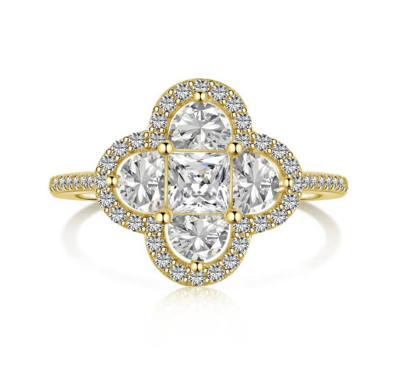 A gold plated ring with a larger central clover piece made up of different shaped white diamonds mainly mini square and semi circular diamonds with miniature white diamonds embroidered around the central piece 