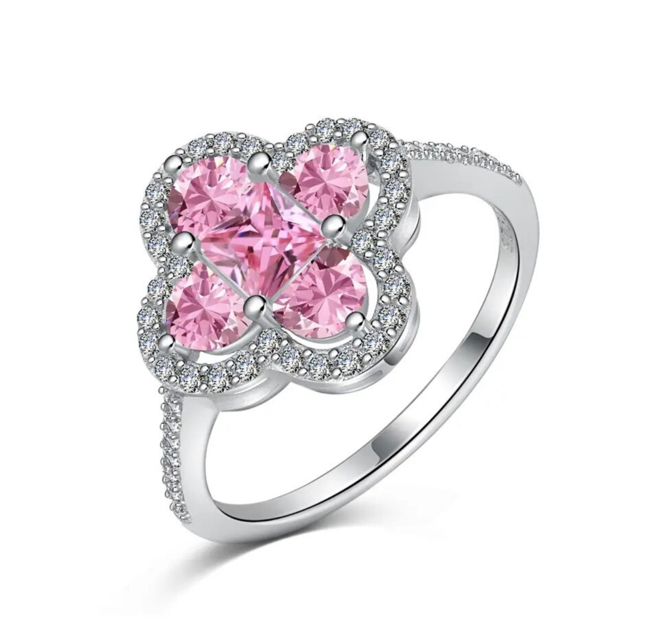 A silver plated ring with a larger central clover piece made up of different shaped medium pink diamonds mainly mini square and semi circular diamonds with miniature white diamonds embroidered around the central piece 